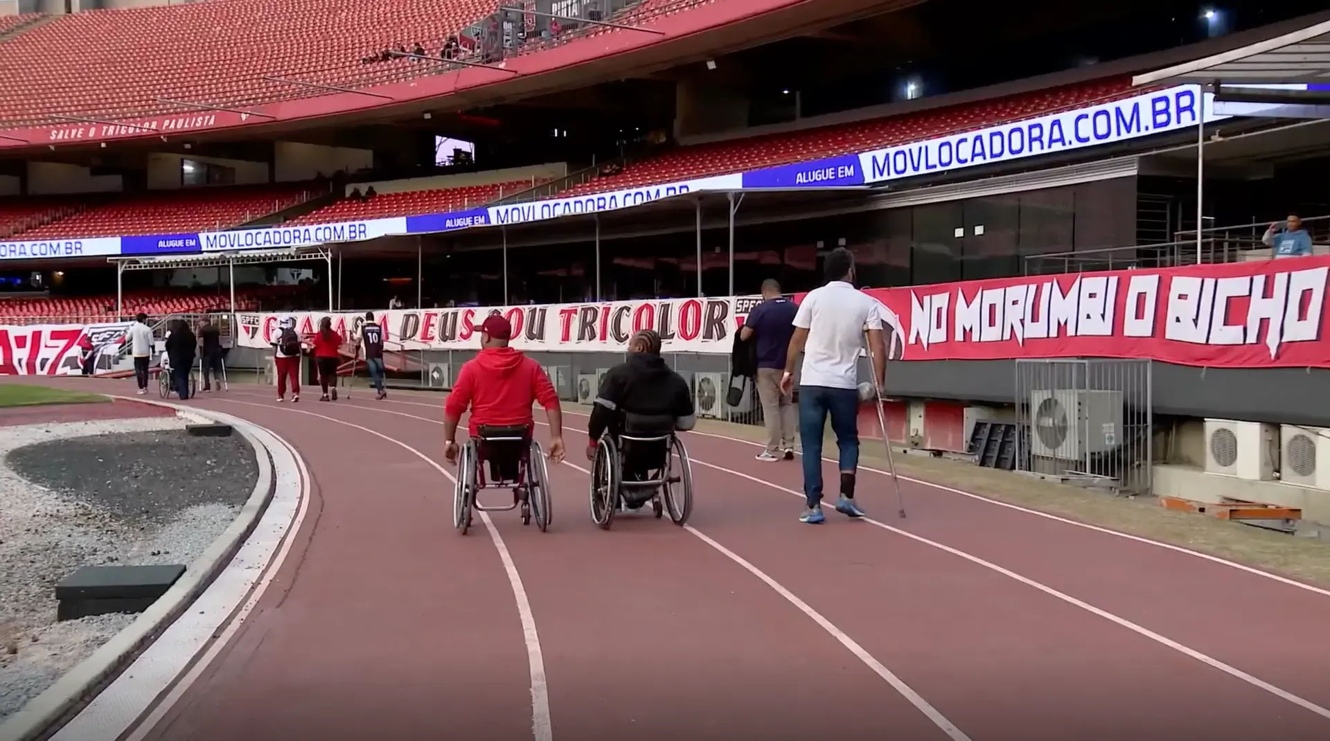 Atletas com cadeiras de rodas e muletas percorrem a pista de atletismo do Estádio do Morumbi durante o Jogo Doe Gols do São Paulo FC.